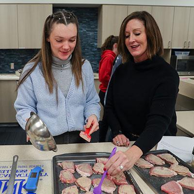 an instructor and student cook food in the nutrition lab